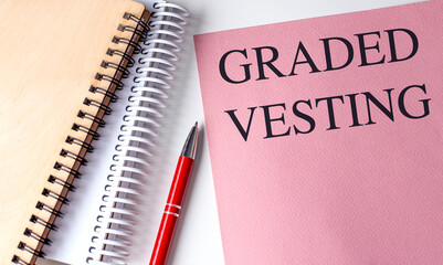 GRADED VESTING text on pink paper with notebooks