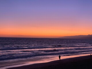 Fototapeta premium Group of people on a sandy beach, watching the sunset in Santa Monica