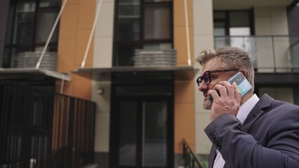 Adult man walking in the city while talking on the phone. Slow motion