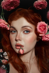 Beauty young redhead woman gazes forward amidst delicately suspended pink roses against a dark...
