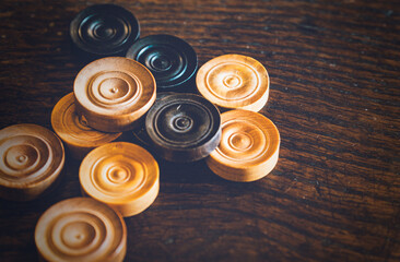 Black and white draughts game pieces on a wooden table
