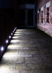 Obraz premium Path with a brick wall illuminated by bright lamps
