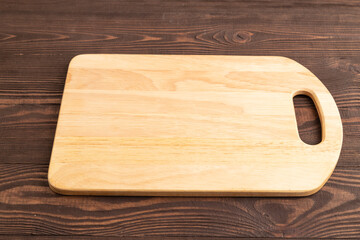 Empty rectangular wooden cutting board on brown wooden. Side view