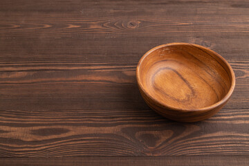 Empty brown wooden bowl on brown wooden. Side view, copy space