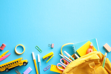 Vibrant School Essentials. A lively and colorful composition featuring a variety of school supplies, including a yellow bus toy, an assortment of pencils, notebooks, and a backpack, on a blue backdrop