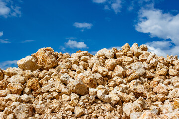 Stone blocks piled in a heap against the background of clouds, stone mining at a limestone quarry