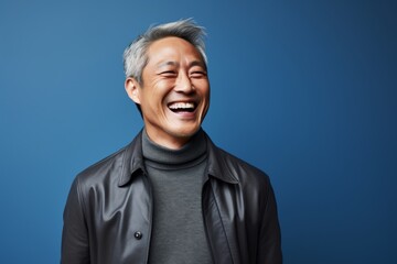 Obraz premium Portrait of a grinning asian man in his 50s laughing in front of scandinavian-style interior background