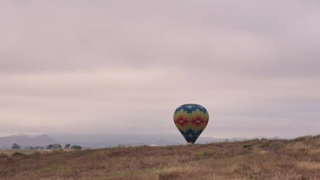 Temecula Balloon and Wine Festival Drone View of Colorful Balloon coming In for a Landing behind hill