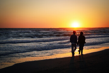 couple walking on beach at sunset
