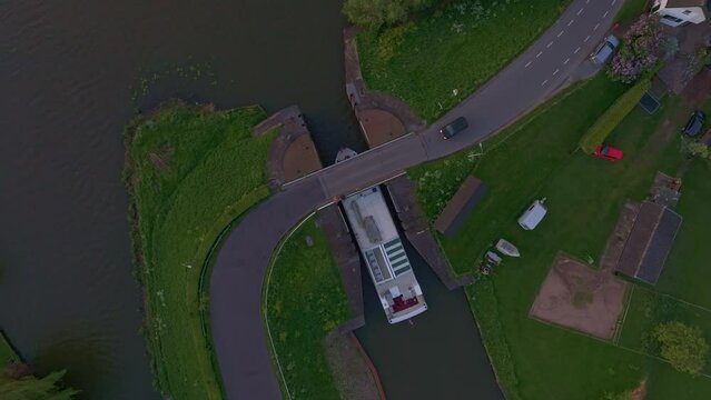 Aerial view of tranquil Linge river at sunset with bridge and boat, Asperen, Netherlands.