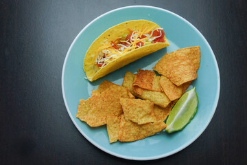 Delicious taco and crispy chips served on a vibrant blue plate