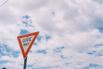 a road sign that reads give way in front of some trees