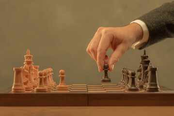 Hand holding chess piece. Chess pieces on the board. Chess player makes a move the black pawn...