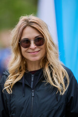 portrait of a woman with sunglasses smiling on blurred background.