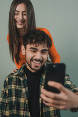 Attractive smiling young couple standing isolated over red background, taking a selfie.