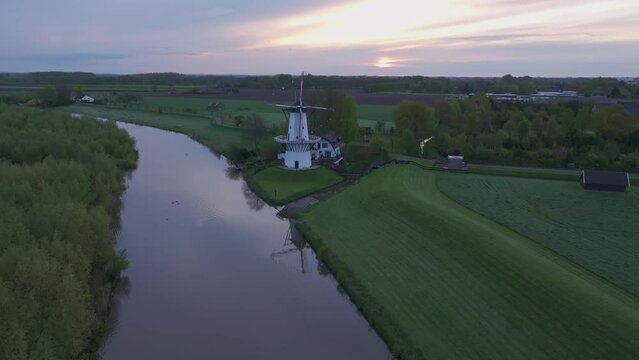 Aerial view of De Vlinder windmill, river Linge, and serene countryside at sunrise, Deil, Netherlands.