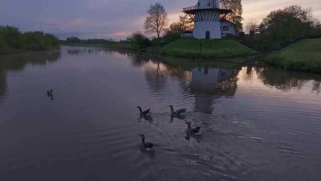 Aerial view of serene river Linge at sunrise with windmill de Vlinder, Deil, Netherlands.