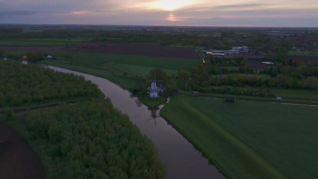 Aerial view of serene sunrise over De Vlinder windmill, river Linge, and farmland, Deil, Gelderland, Netherlands.