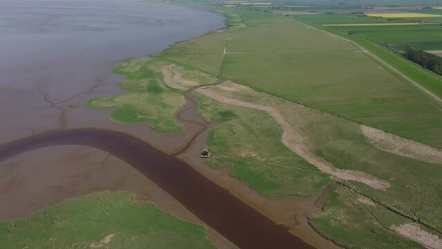 Aerial view of meandering river, birdwatcher's hut, wetlands, and Wadden Sea, Kiekkaaste, Groningen, Netherlands.