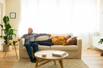 Senior married couple relaxing on a sofa in their living room. Senior couple lying down on a sofa...