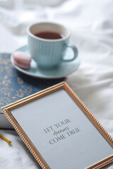 Golden frame on a bed near coffee and a cookie