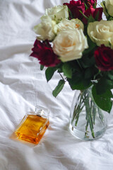 Glass vase with flowers, soap, and bottle displayed on a bed