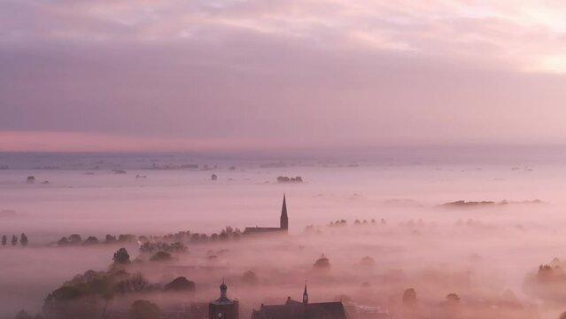 Aerial view of foggy sunrise over church and city, Workum, Friesland, Netherlands.