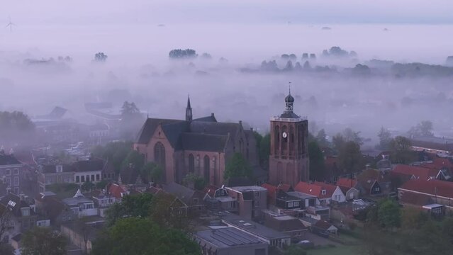 Aerial view of foggy city with historic church and rooftops, Workum, Friesland, Netherlands.