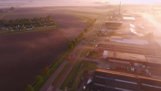 Aerial view of industrial factory, fields, road, and buildings in foggy Workum, Friesland, Netherlands.