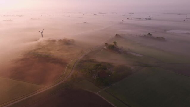 Aerial view of misty farm fields with wind turbines at sunrise, Workum, Friesland, Netherlands.