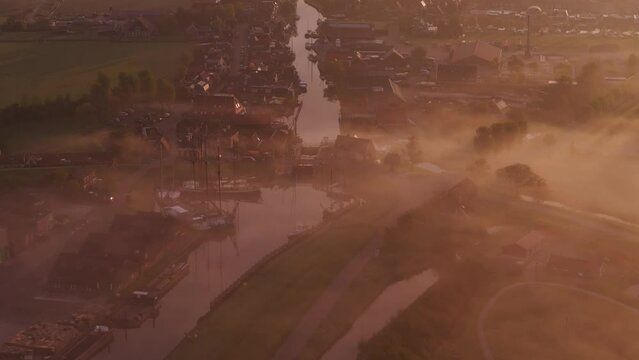 Aerial view of foggy city with canal, church, and rooftops in Workum, Friesland, Netherlands.