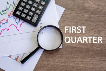 Top view image text FIRST QUARTER on office desk. First quarter concept.