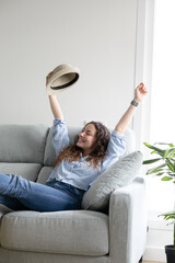 woman with arms raised celebrates good news. Happy woman with her straw hat on vacation.
