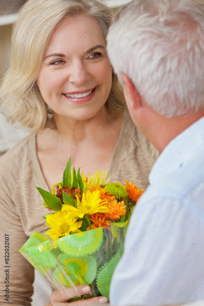 Wall mural happy senior man and woman couple with flowers smiling at home