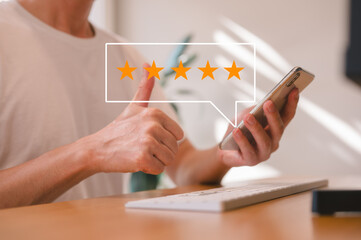 feedback and Customer service satisfaction survey concept, customer man hand pressing on smartphone screen with gold five star rating feedback icon