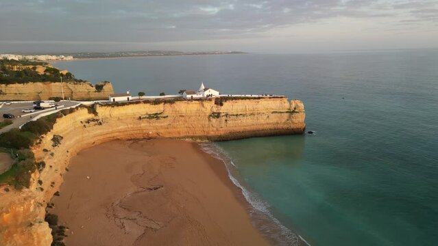 Aerial view of rocky cliffside beach with church overlooking the ocean, Ermida de Nossa Senhora da Rocha, Porches, Algarve, Portugal.