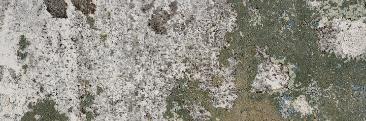 Peeling paint on the wall. Panorama of a concrete wall with old cracked flaking paint. Weathered rough painted surface with patterns of cracks and peeling. Wide panoramic texture for design background