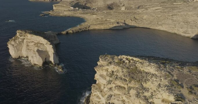 Aerial view of rugged cliffs and rocky coast by the sea, Gozo cliffs, Dwejra Bay, Munxar, Malta.