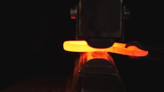 Craft workshop for manufacture of metal structures. blacksmith is working.  handmade forge. master makes iron products, beats hot metal with an industrial hammer and gives shape