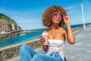 Woman with curly hair drinking iced juice at promenade