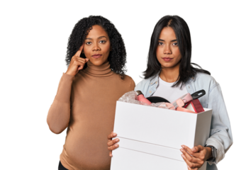 Latin women couple moving, one pregnant  pointing temple with finger, thinking, focused on a task.
