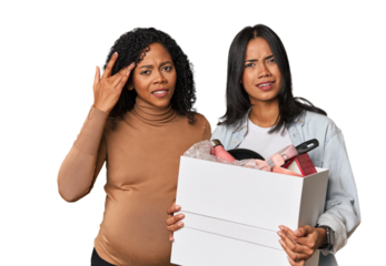 Latin women couple moving, one pregnant  showing a disappointment gesture with forefinger.