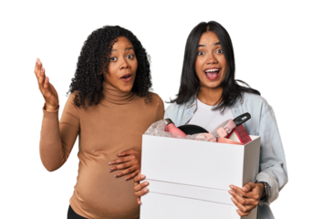 Latin women couple moving, one pregnant  receiving a pleasant surprise, excited and raising hands.