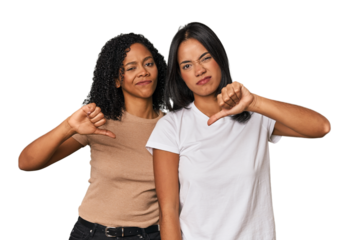 Young Latin friends in studio showing thumb down, disappointment concept.