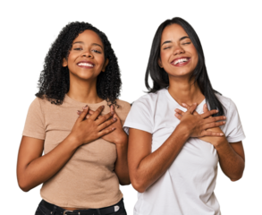 Young Latin friends in studio laughing keeping hands on heart, concept of happiness.