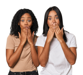 Young Latin friends in studio shocked, covering mouth with hands, anxious to discover something new.