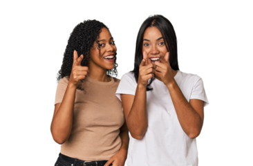 Young Latin friends in studio pointing to front with fingers.