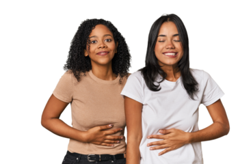 Young Latin friends in studio touches tummy, smiles gently, eating and satisfaction concept.