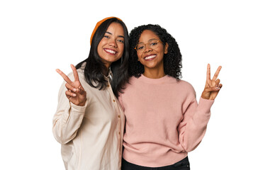 Young Latin friends together in studio showing victory sign and smiling broadly.