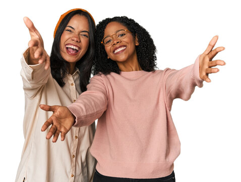 Young Latin friends together in studio feels confident giving a hug to the camera.